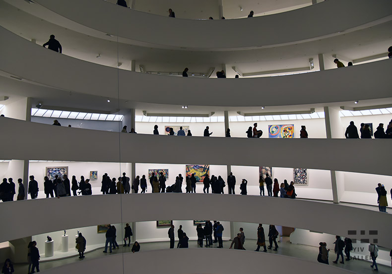 Посетители музея современного искусства Соломона Гуггенхайма. Люди ходят возле картин и скульптур